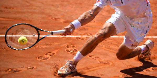 网球运动员在红土场上奋力击球的动作